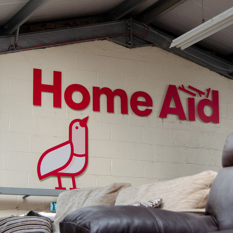 Large Home Aid logo signage displayed on a white brick wall