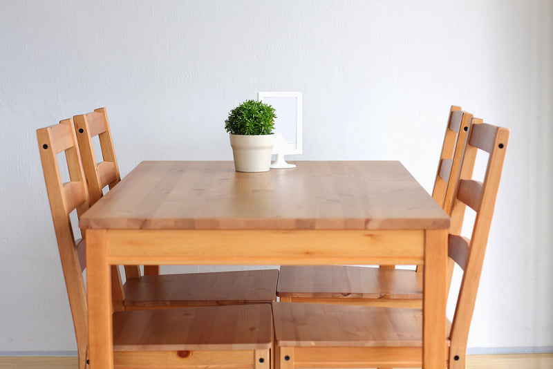 Wooden dining table with 4 chairs and small plant in the centre